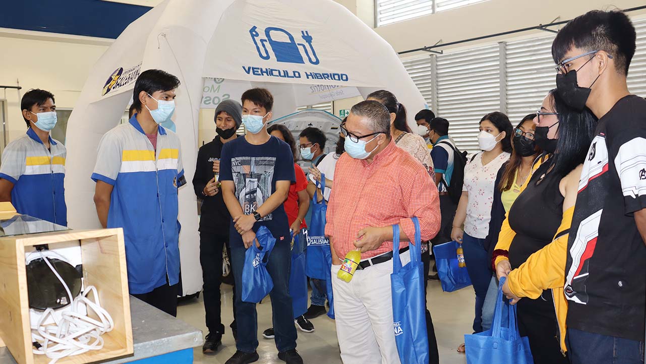 Automotive engineering students showing high school students one of the laboratories