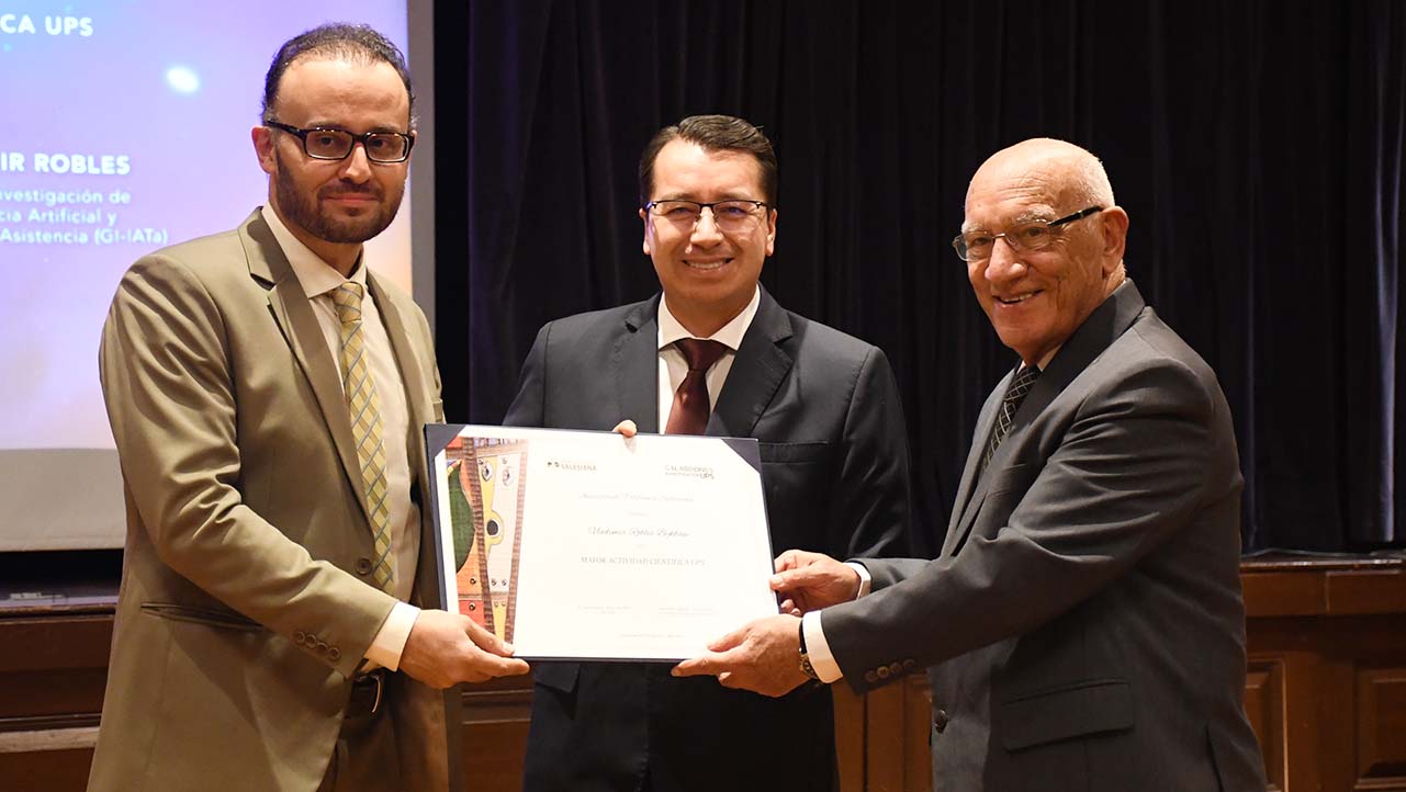 Vladimir Robles gets an award from Juan Cárdenas, UPS president, and Javier Herrán, former UPS president